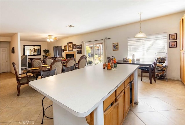 kitchen featuring ceiling fan, a kitchen island, hanging light fixtures, and light tile patterned floors