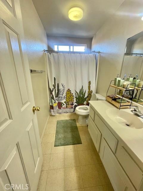 bathroom featuring a shower with shower curtain, vanity, and toilet