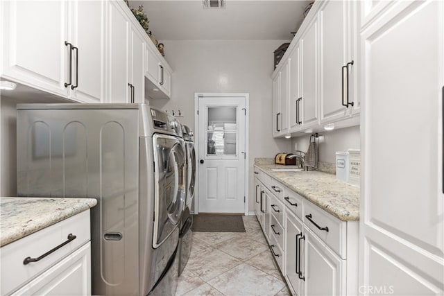 clothes washing area with sink, washer and dryer, and cabinets