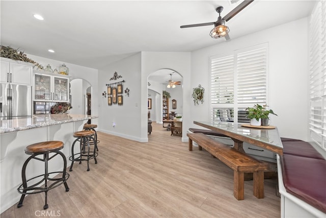 kitchen with light wood-type flooring, stainless steel fridge, white cabinetry, and plenty of natural light