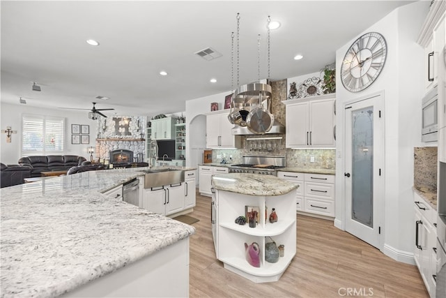 kitchen with light stone counters, a fireplace, a kitchen island, and sink