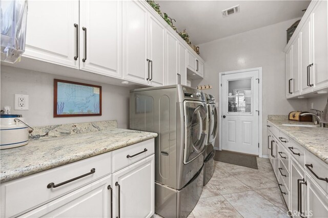 clothes washing area featuring cabinets, sink, and washing machine and dryer