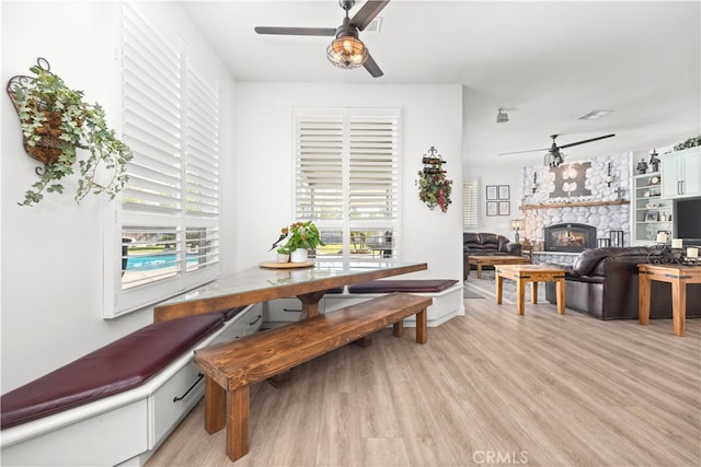 dining area with light wood-type flooring, a fireplace, and a wealth of natural light