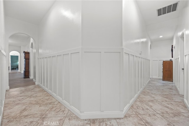 hallway with high vaulted ceiling and light tile patterned flooring