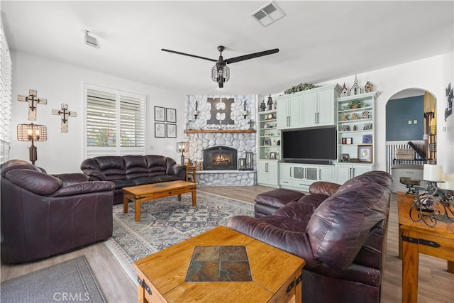 living room with wood-type flooring, a fireplace, and ceiling fan