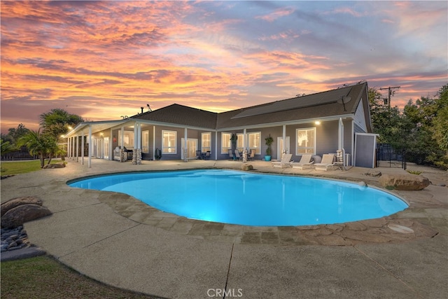 pool at dusk featuring a patio area