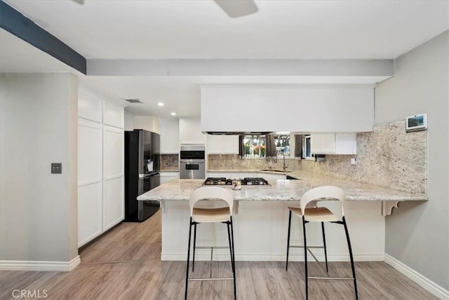 kitchen with kitchen peninsula, white cabinetry, a breakfast bar area, and sink