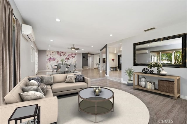 living room featuring a wall mounted AC, ceiling fan, and wood-type flooring