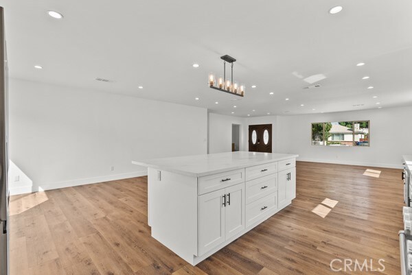 kitchen featuring white cabinets, a center island, hanging light fixtures, and light wood-type flooring