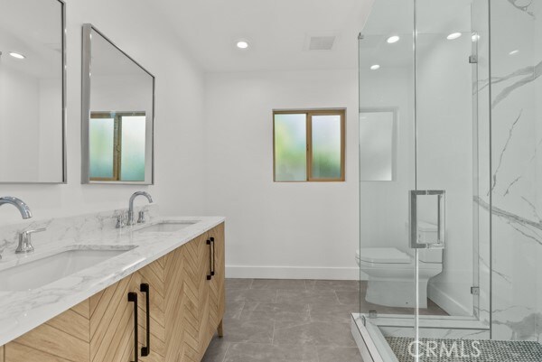 bathroom featuring toilet, walk in shower, and vanity