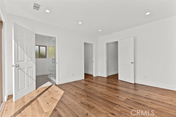 unfurnished bedroom featuring ensuite bathroom and hardwood / wood-style flooring