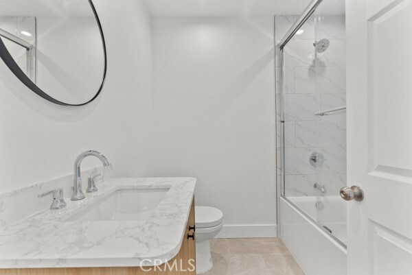 full bathroom featuring vanity, bath / shower combo with glass door, toilet, and tile patterned flooring