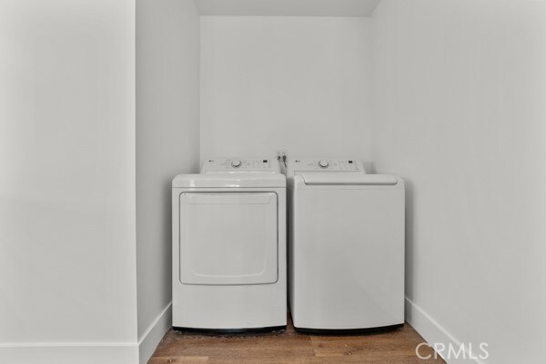 laundry room with washing machine and clothes dryer and hardwood / wood-style floors