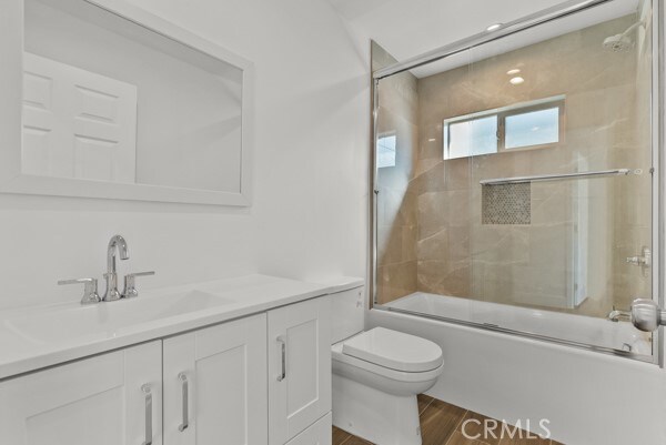 full bathroom with vanity, bath / shower combo with glass door, wood-type flooring, and toilet