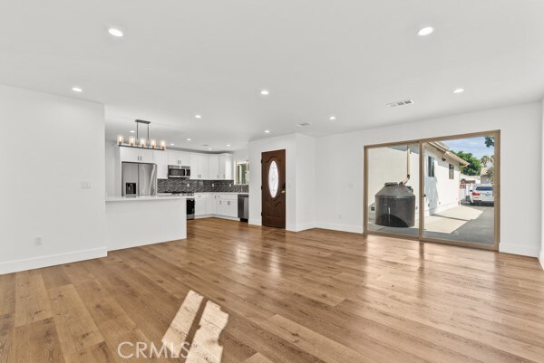 unfurnished living room with light hardwood / wood-style floors and an inviting chandelier