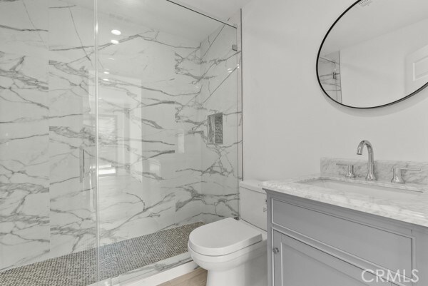 bathroom with toilet, vanity, and a shower with door