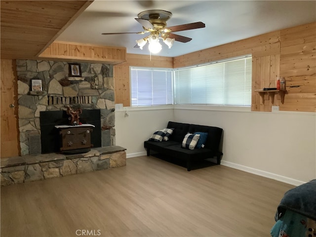 sitting room featuring ceiling fan, hardwood / wood-style flooring, and a wood stove