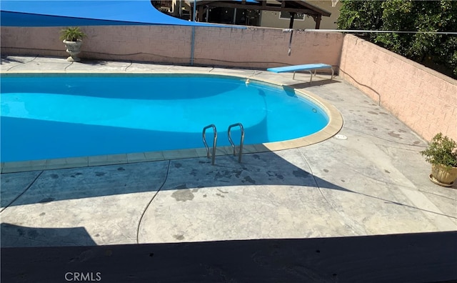 view of swimming pool with a diving board