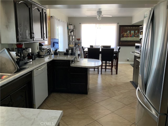 kitchen with ceiling fan, white dishwasher, light tile patterned floors, kitchen peninsula, and stainless steel refrigerator