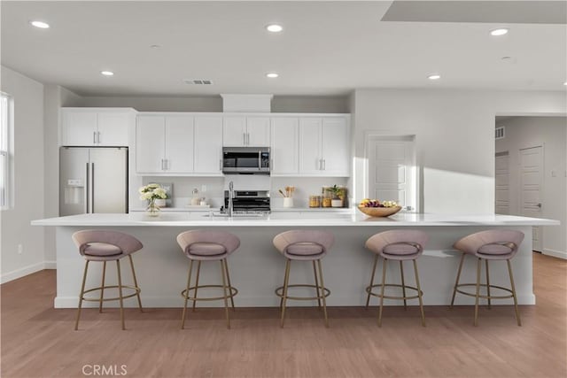 kitchen with white cabinetry, stainless steel appliances, and a breakfast bar area