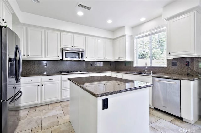 kitchen with sink, dark stone countertops, a kitchen island, white cabinetry, and stainless steel appliances