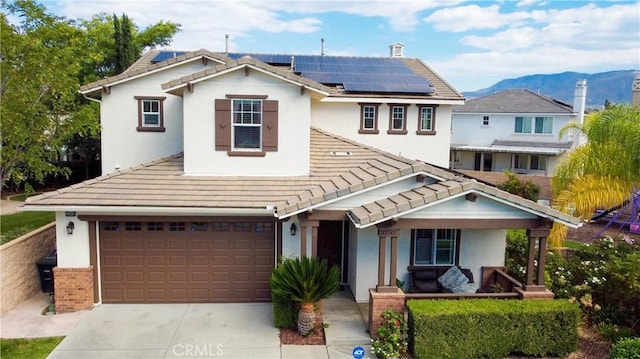 view of front of house with covered porch, solar panels, a garage, and a mountain view