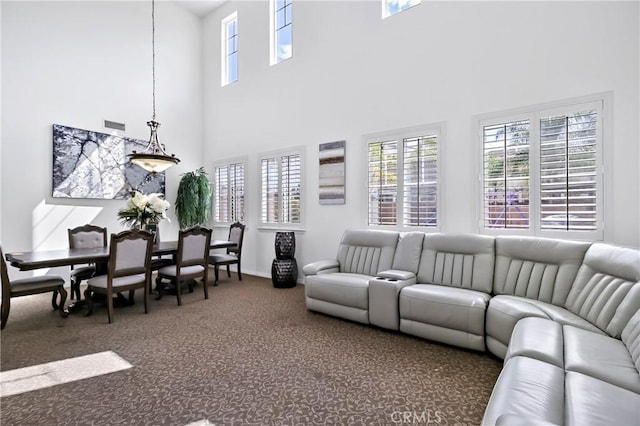 living room with a towering ceiling and dark carpet