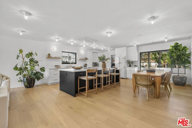 kitchen featuring white cabinetry, a center island, light wood-type flooring, and a kitchen breakfast bar