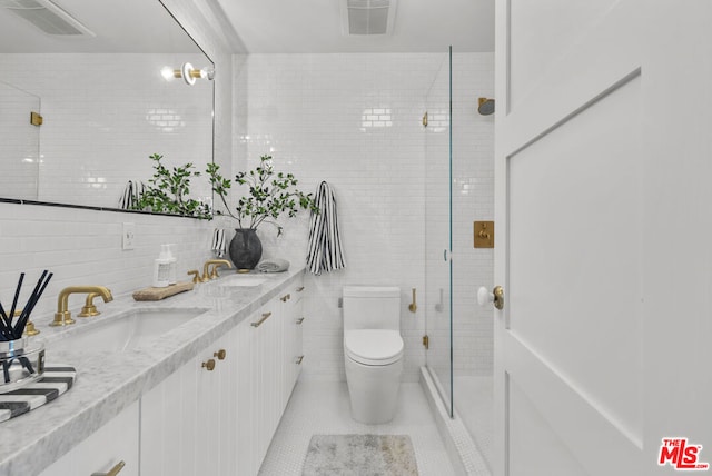 bathroom featuring a shower with door, backsplash, toilet, tile walls, and vanity