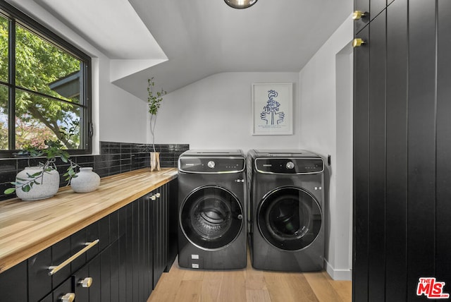 laundry room with washer and dryer, cabinets, and light wood-type flooring