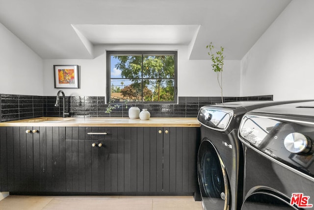 laundry area featuring sink, light tile patterned floors, cabinets, and washer and clothes dryer