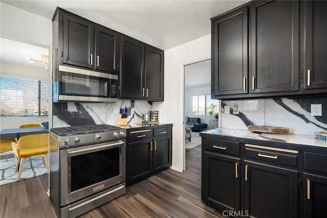 kitchen with appliances with stainless steel finishes, dark hardwood / wood-style floors, tasteful backsplash, and a healthy amount of sunlight