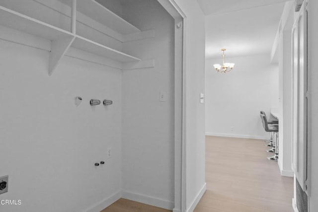 laundry area featuring hardwood / wood-style floors, electric dryer hookup, and a notable chandelier