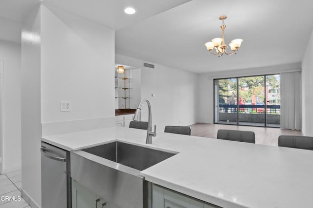 kitchen featuring pendant lighting, dishwasher, sink, light tile patterned flooring, and a chandelier