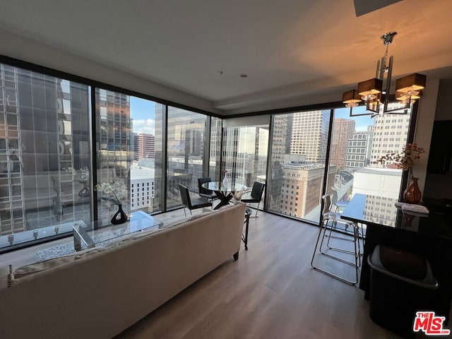 living room with a wall of windows, an inviting chandelier, and wood-type flooring