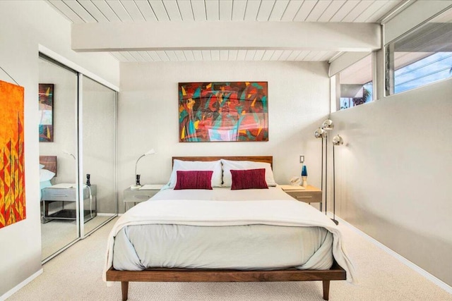 carpeted bedroom with beamed ceiling, a closet, and wood ceiling