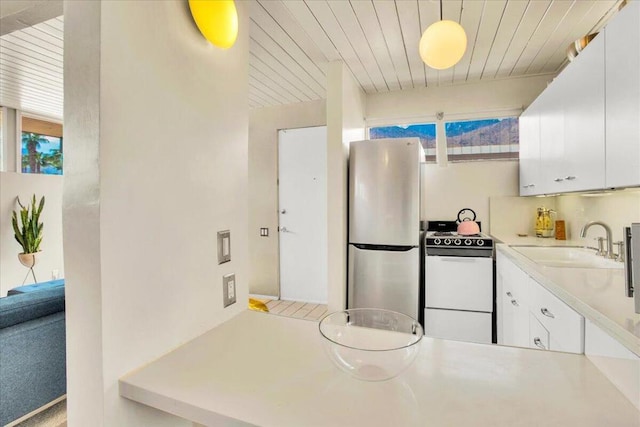 kitchen with stainless steel refrigerator, white cabinetry, hanging light fixtures, and white range