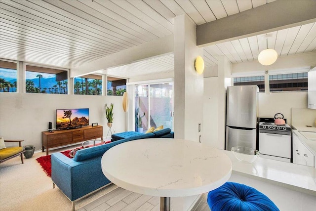 interior space with beam ceiling, light hardwood / wood-style floors, and a wealth of natural light