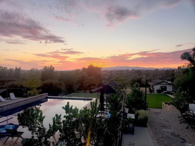 pool at dusk featuring a patio area