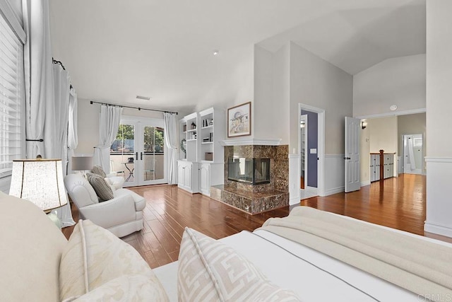 living room featuring high vaulted ceiling, wood-type flooring, a high end fireplace, and french doors