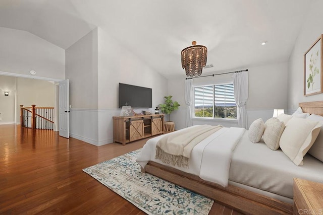 bedroom featuring hardwood / wood-style flooring, lofted ceiling, and an inviting chandelier