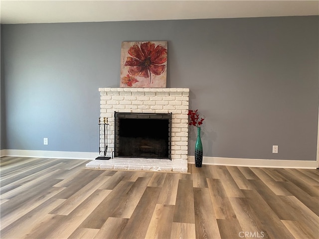 unfurnished living room with a brick fireplace and hardwood / wood-style flooring