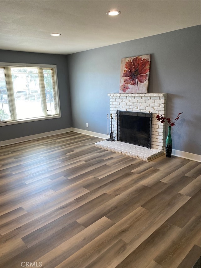 unfurnished living room with a brick fireplace and dark hardwood / wood-style floors