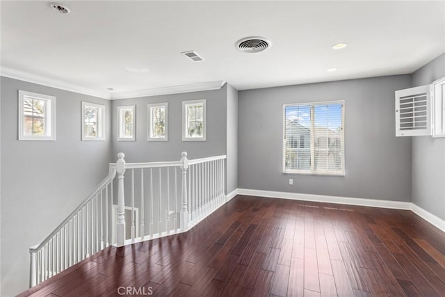 spare room featuring dark hardwood / wood-style floors, crown molding, and a wealth of natural light