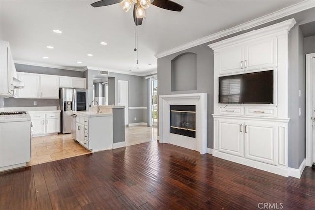 kitchen featuring white range oven, ceiling fan, hardwood / wood-style flooring, white cabinetry, and an island with sink