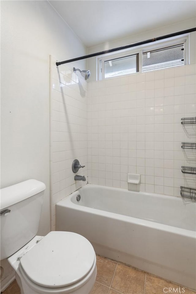 bathroom with toilet, tile patterned flooring, and tiled shower / bath