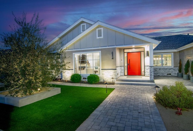 view of front facade with a front yard, board and batten siding, and stone siding