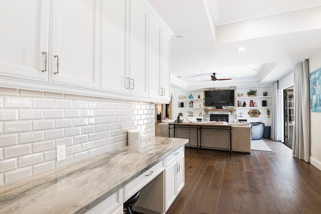 kitchen with ornamental molding, light stone counters, white cabinets, a ceiling fan, and dark wood-style flooring