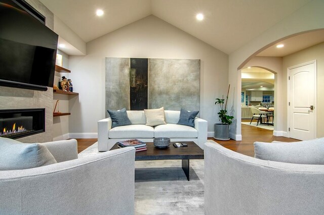 living room featuring lofted ceiling, hardwood / wood-style floors, and a large fireplace