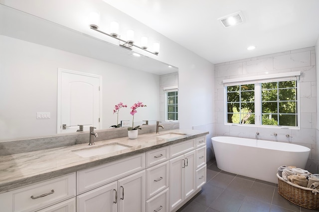 bathroom with vanity, tile walls, a bath, and tile patterned floors